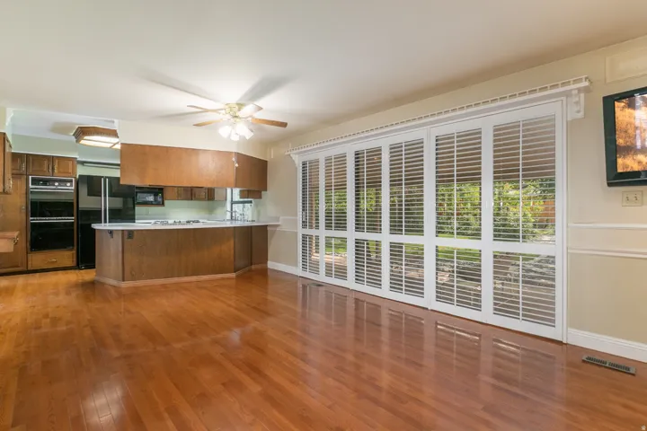 Hardwood flooring throughout, kitchen with built-in double ovens, breakfast bar, and ceiling fan