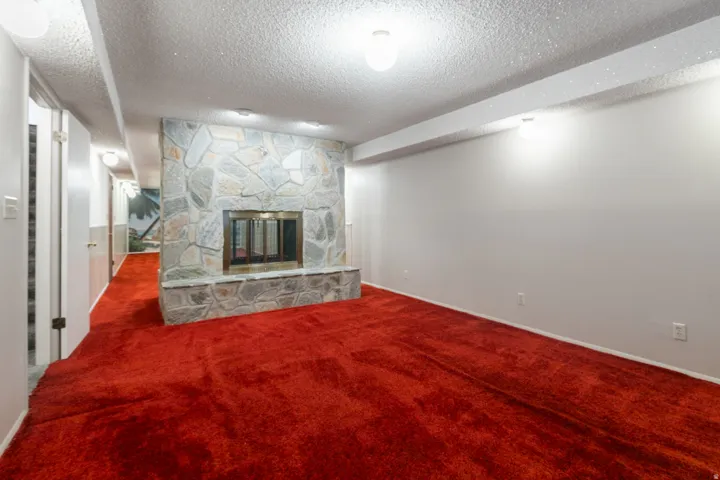 Stone-clad fireplace with hearth, red carpeting, and recessed lighting