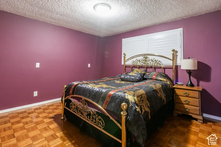 Parquet wood flooring, ceiling light fixture, window with white louvered shutters, and purple walls