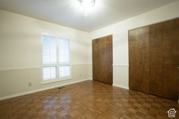Parquet wood flooring, floor-to-ceiling bi-fold closet doors, wall-mounted shutters, and chair rail molding