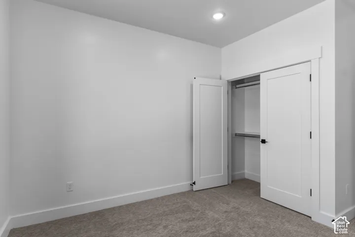Recessed ceiling lighting, white walls, carpet flooring, flat panel closet doors, and built-in closet shelving