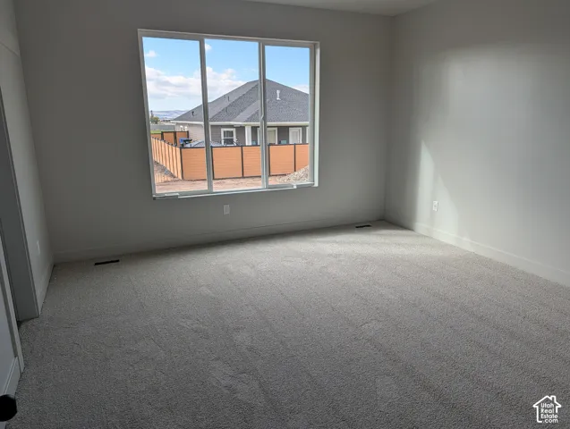 Spacious room featuring neutral carpeting, light-toned wall paint, and a large multi-pane window