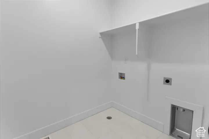 Dedicated utility space featuring built-in shelving, a floor drain, and a stainless steel utility sink