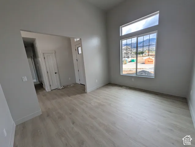 Vaulted ceilings, wood-finish flooring, oversized window with transom, mountain backdrop, and neutral wall color