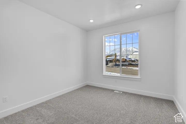 Neutral gray carpet, white walls, recessed lighting, and a multi-pane window with mountain scenery