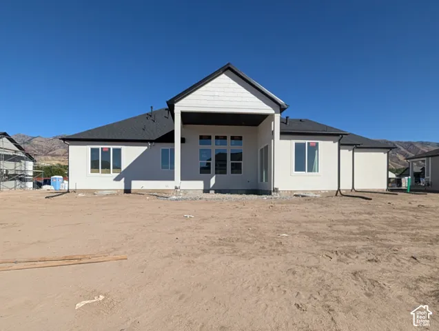 Newly constructed residence featuring stucco siding, shingle roofing, and a prominent covered patio area