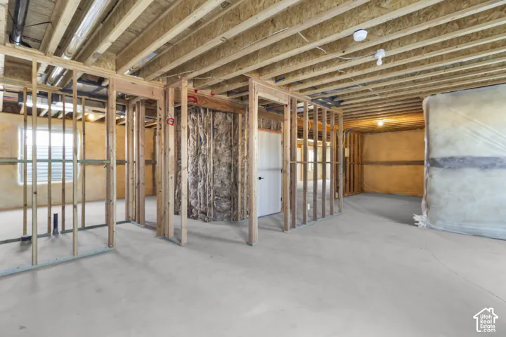 Unfinished lower level featuring wood framing, exposed ceiling joists, and a concrete floor