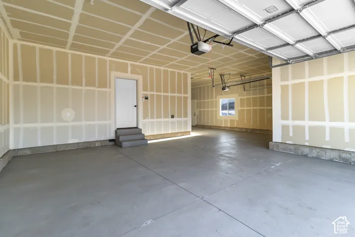 Expansive garage space featuring concrete flooring, a full-size window, and an interior access door with steps