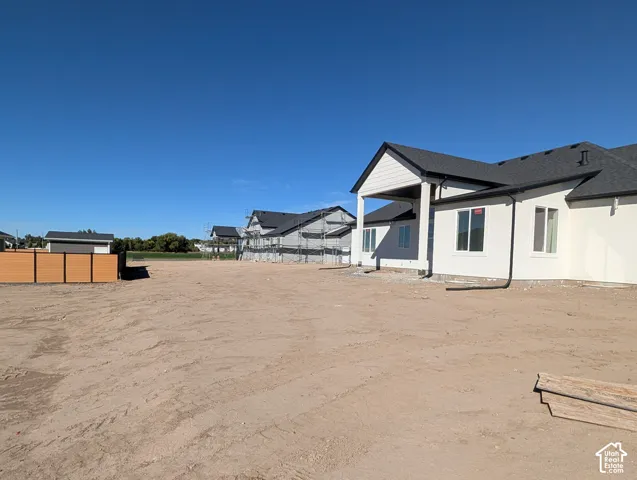 Expansive undeveloped lot with a newly constructed residence featuring white siding and a covered porch entry