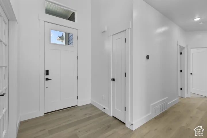 Entryway featuring a solid panel door with a transom window, wood-finish flooring, and crisp white trim
