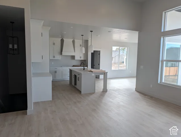 Kitchen featuring white shaker-style cabinetry, central island with stone-surface countertop, matte black hardware, wood-finish flooring, and multi-pane windows