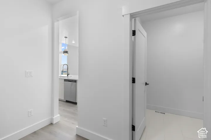 Wood-finish flooring, white walls, and a white door with black hardware