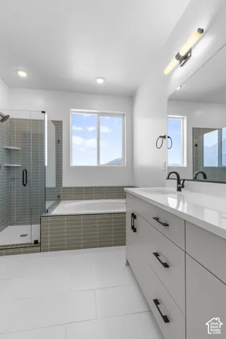 Spacious bathroom featuring a double vanity, a glass-enclosed shower, a built-in soaking tub, and a window for natural light