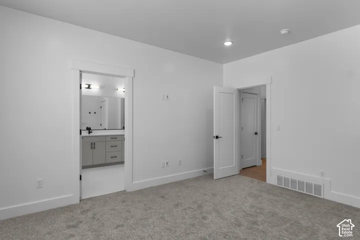 Neutral carpeted flooring, white walls, recessed ceiling lighting, and solid core doors with matte black hardware