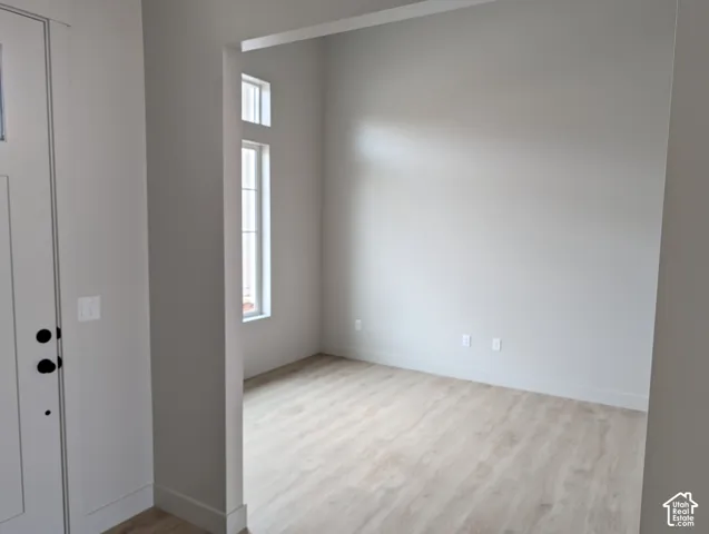 High-ceiling room featuring neutral paint, wood-finish flooring, and multi-pane windows