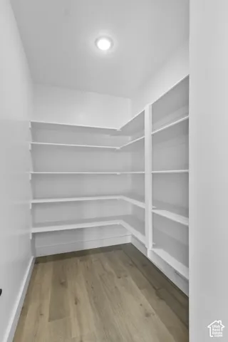 Integrated recessed lighting illuminates the space, featuring extensive built-in shelving, white walls, and wood-finish flooring