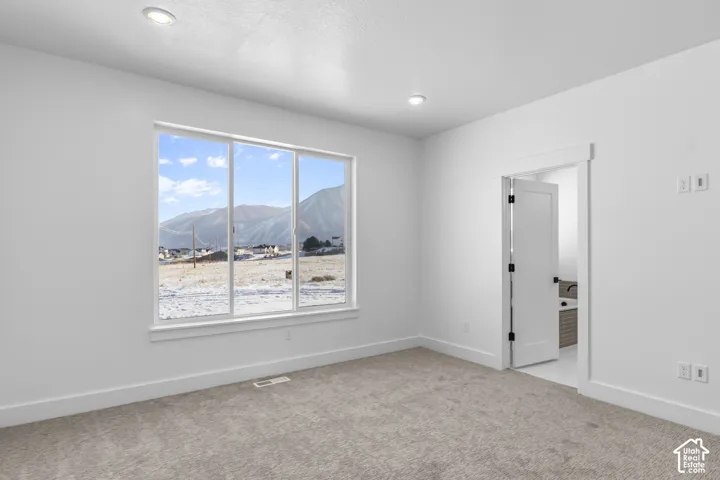 Recessed lighting, light-toned carpeting, white walls, white trim, and a window framing a mountain backdrop