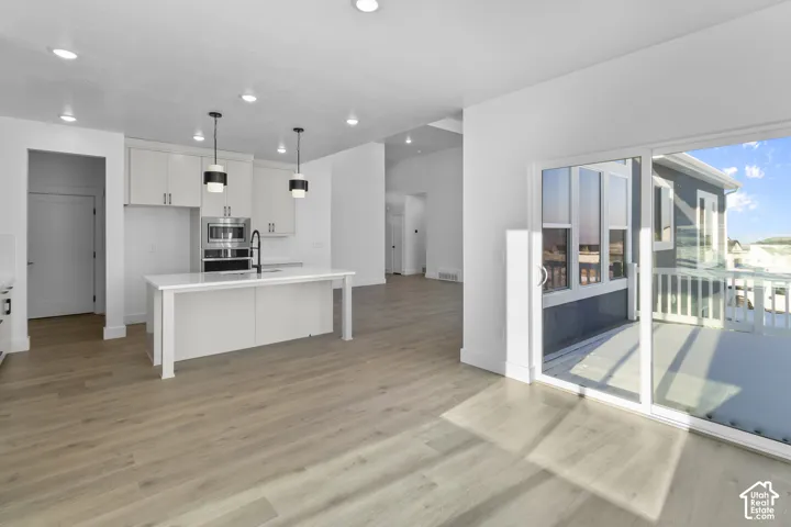 Open-concept kitchen with stainless steel appliances, large center island, and contemporary pendant lighting