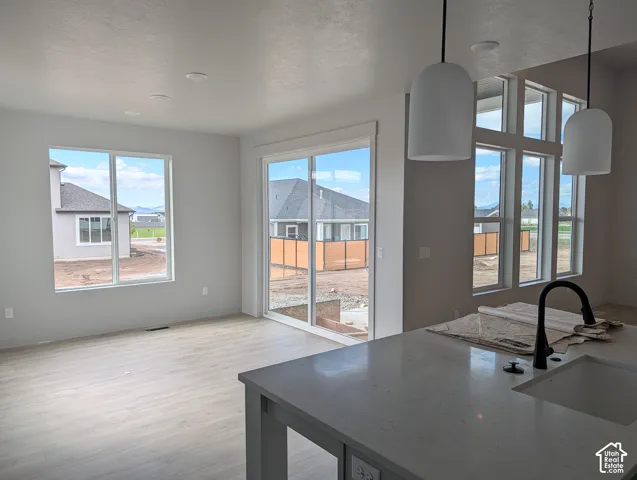 Open-concept interior featuring wood-finish flooring, floor-to-ceiling windows, sliding glass door, center island with stone-surface countertop, and matte black plumbing fixtures