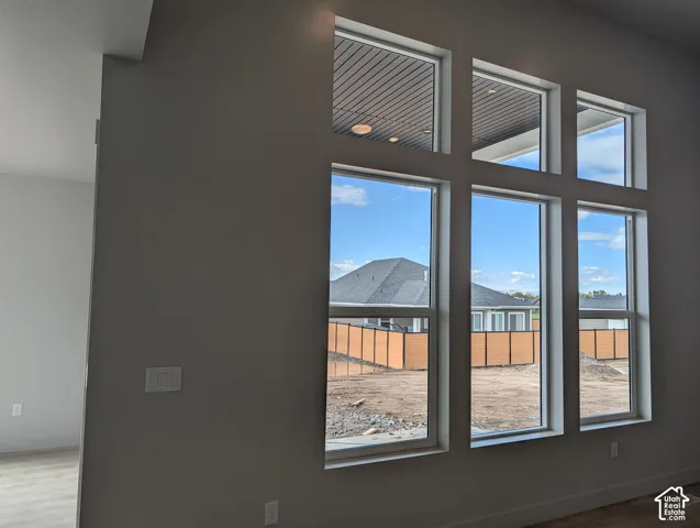 Floor-to-ceiling windows with white frames, clean-lined interior walls, and light-toned wood-finish flooring