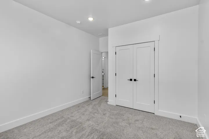 Recessed lighting, light gray carpeting, white walls, white doors with matte black hardware, and white trim