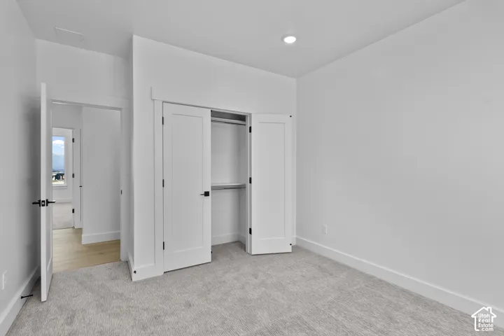 Recessed ceiling lighting, white walls, light gray carpeting, two-panel interior doors, and matte black door hardware