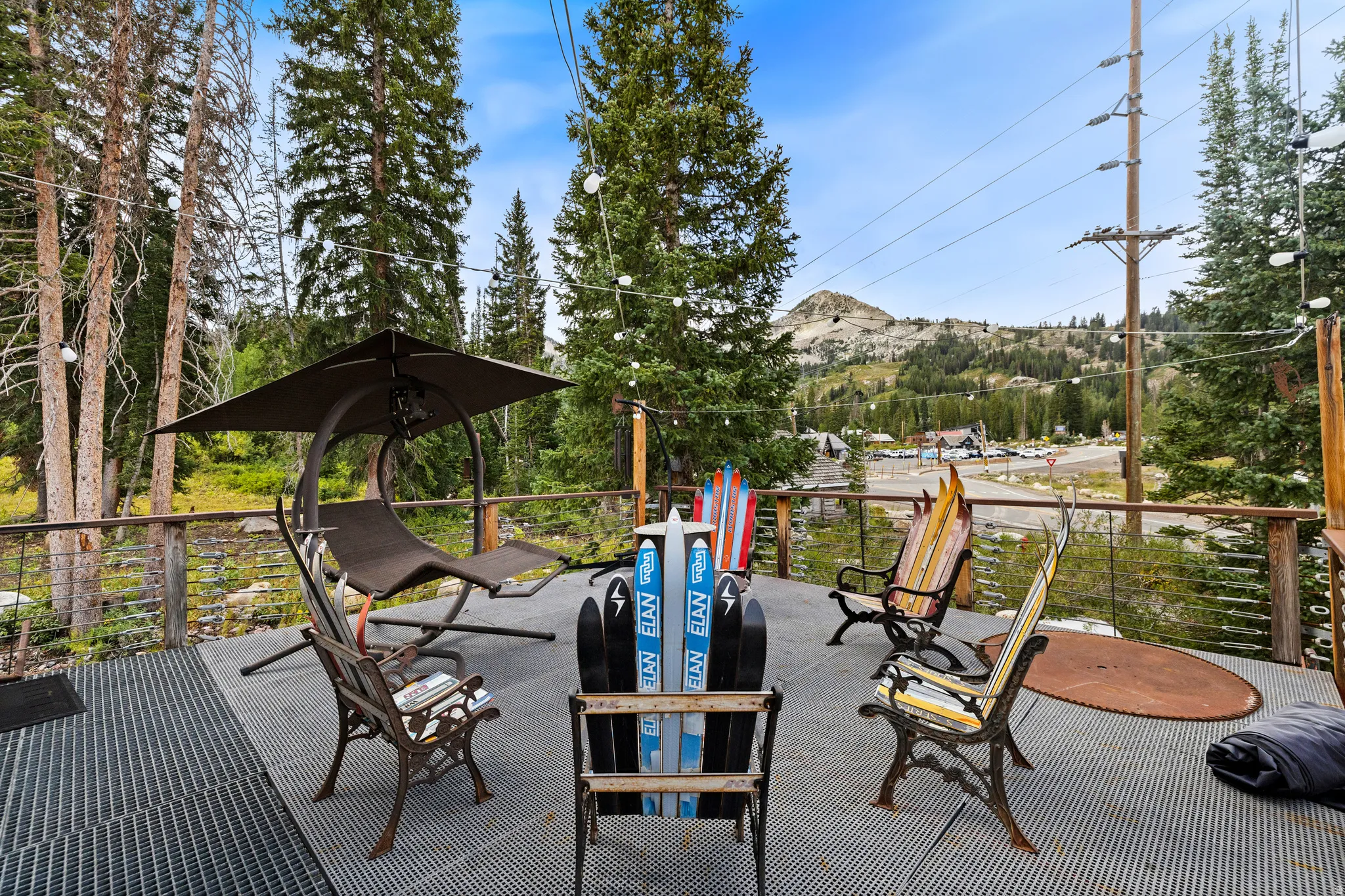 Spacious outdoor deck featuring metal grating, wood railing, string lighting, and extensive tree coverage