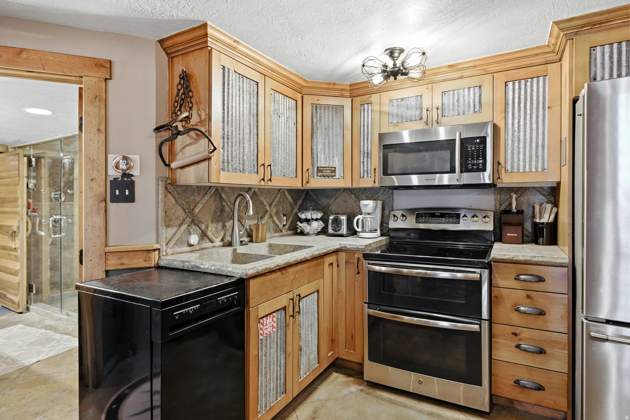 Wood-finish cabinetry with corrugated metal inserts, stainless steel appliances, and a tile backsplash
