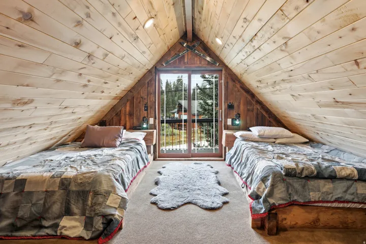 Sloped wood-paneled ceiling, wood-finish walls, built-in wooden nightstands, recessed ceiling lighting, and glass-paneled doors