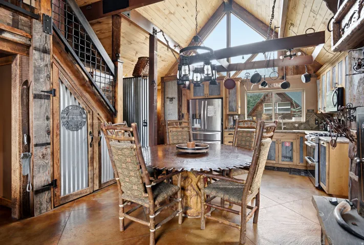 Vaulted wood-paneled ceiling with exposed beams, stainless steel appliances, and a built-in pot rack