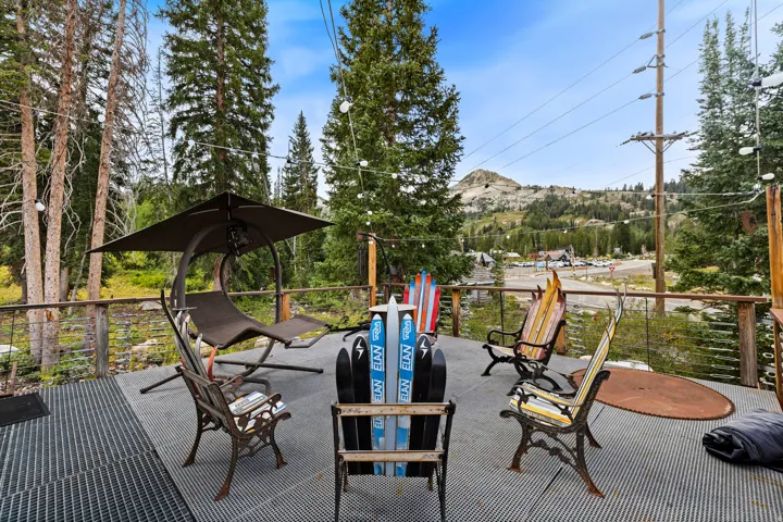Spacious outdoor deck featuring metal grating, wood railing, string lighting, and extensive tree coverage