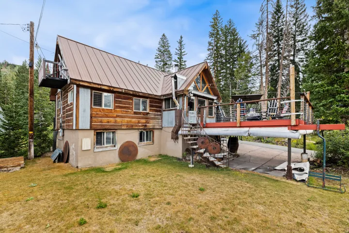 Exterior featuring wood siding, metal roofing, an elevated deck, and a lower-level concrete patio