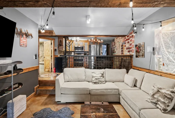 Exposed wood beams, concrete flooring, wood paneling, metal railing, and recessed lighting
