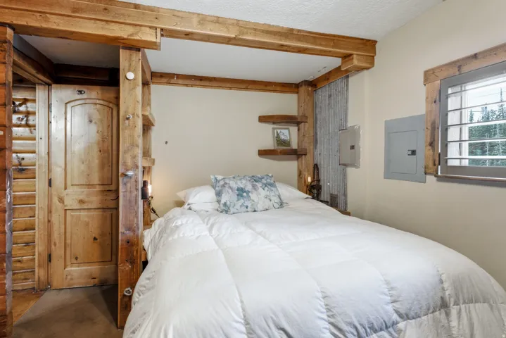 Wood-paneled accent wall, wood-finish door, exposed wood beams, wood-framed window, and integrated wood shelving