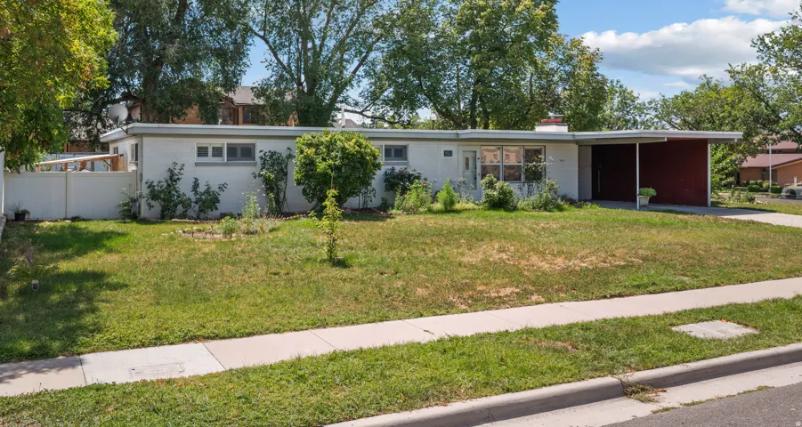 Single-story residence featuring a carport, a front sidewalk, and a partially fenced perimeter