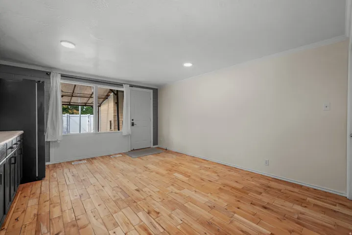 Wood-finish flooring throughout, recessed ceiling lighting, built-in cabinetry with light-toned countertops, and a white entry door