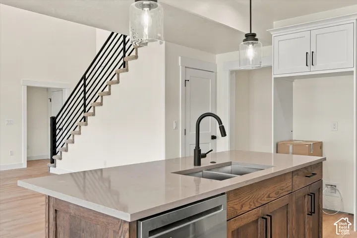 Kitchen island with a light-toned countertop, dual basin sink, and matte black faucet