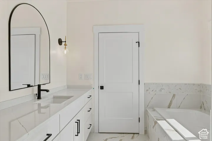 Double vanity with white cabinetry, integrated sinks, and polished countertops