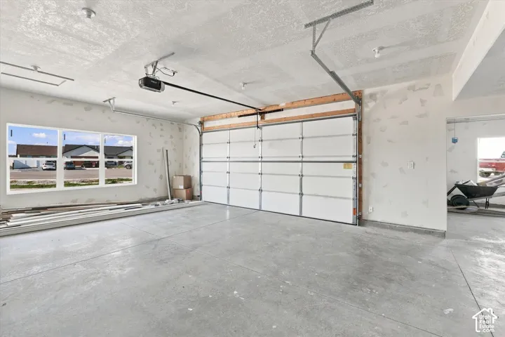 Spacious garage with a concrete floor, overhead lighting, and an automatic garage door opener
