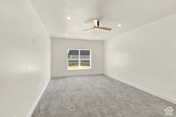 Vaulted ceiling with recessed lighting and ceiling fan, white trim, grey carpeting, and a window with white framing
