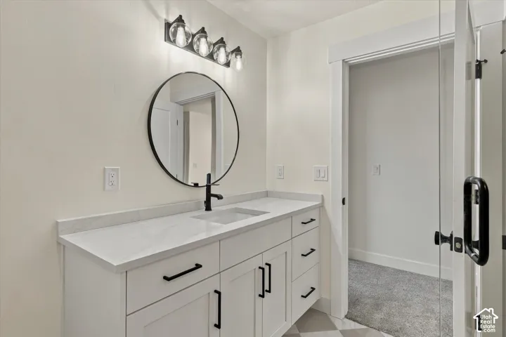 White vanity with a solid surface countertop, an undermount sink, and a matte black faucet