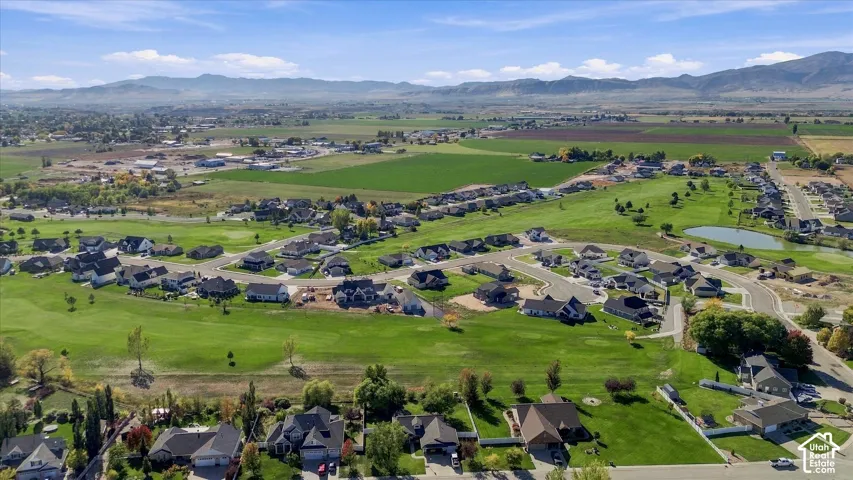 Expansive residential development with manicured green spaces, a water feature, and mountain backdrops