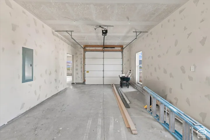 Concrete flooring, overhead garage door, overhead garage door opener, interior window, wall-mounted electrical panel