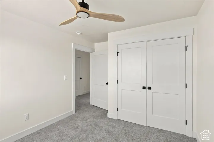 Recessed ceiling fan with wood-finish blades, white paneled doors with black hardware, and light gray carpet flooring