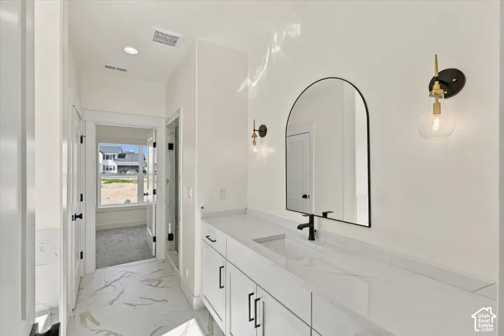 Dual vanity with white cabinetry, integrated sink, black fixtures, and arch-top mirror, complemented by patterned flooring