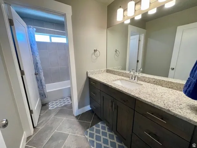 Upstairs full bath; Vanity with a speckled countertop, undermount sink, and dark wood-finish cabinetry