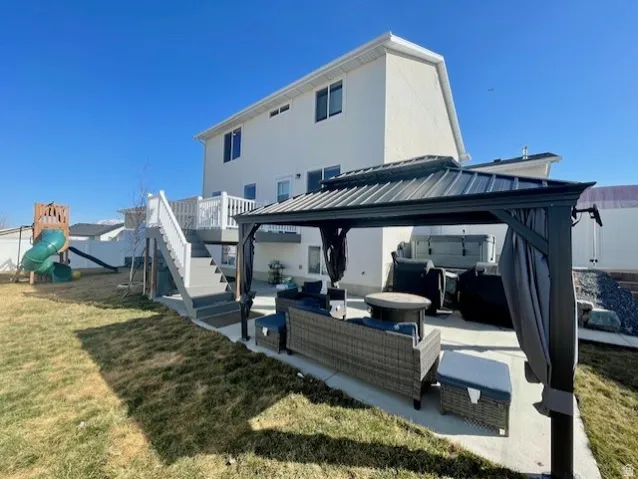 Rear exterior featuring a two-story design, white siding, and multiple windows.  Backyard gazebo and covered patio/deck area.