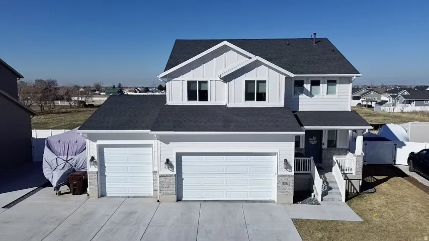Two-story residence with a multi-gable roofline, two-car garage, board and batten siding accents, and a covered entry with railings