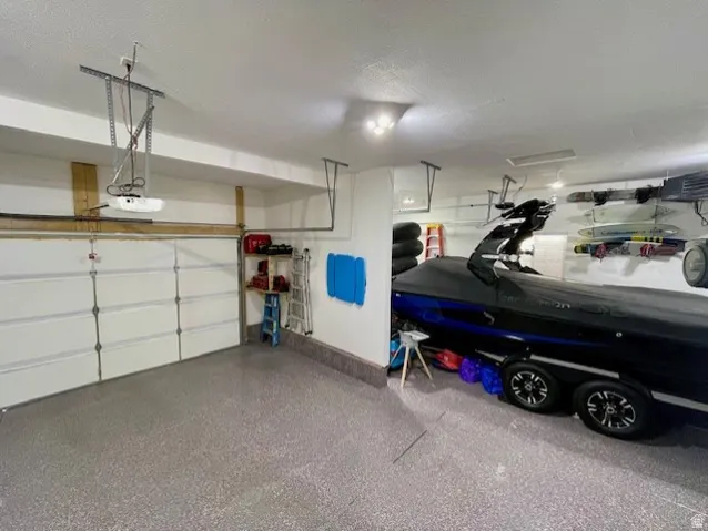 Garage - great for boat parking; featuring a speckled epoxy floor, white paneled garage door, and ceiling-mounted garage door opener