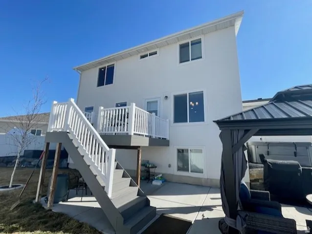 Two-story exterior with white siding, ground-level patio, and an upper-level deck with white railing